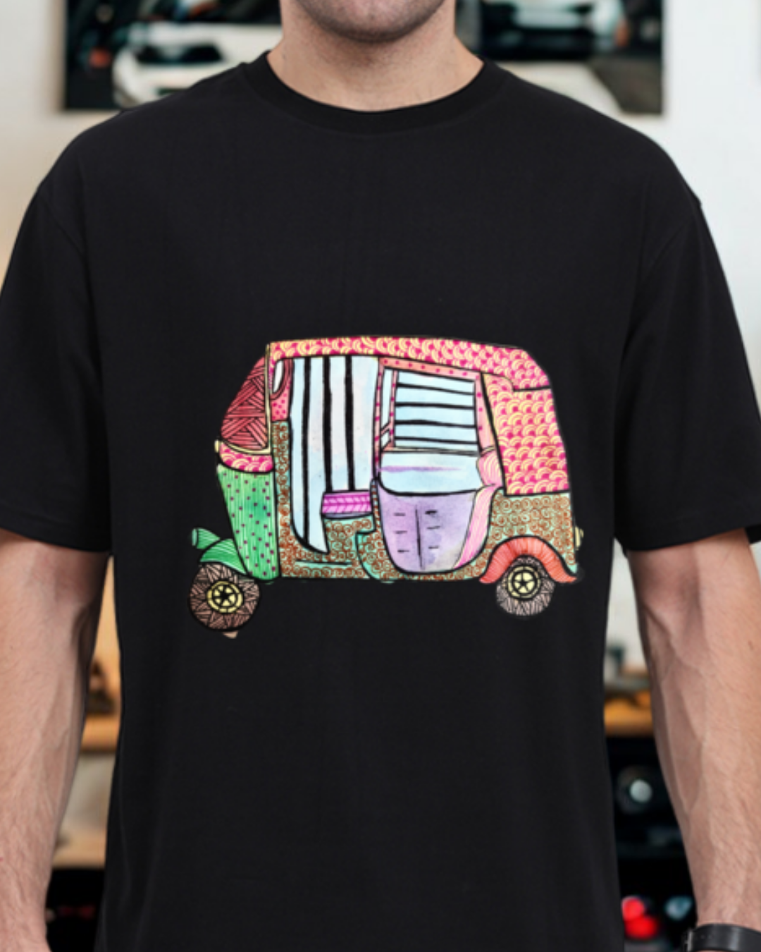 Black t-shirt with a colorful graphic of a vehicle on a blurred indoor background